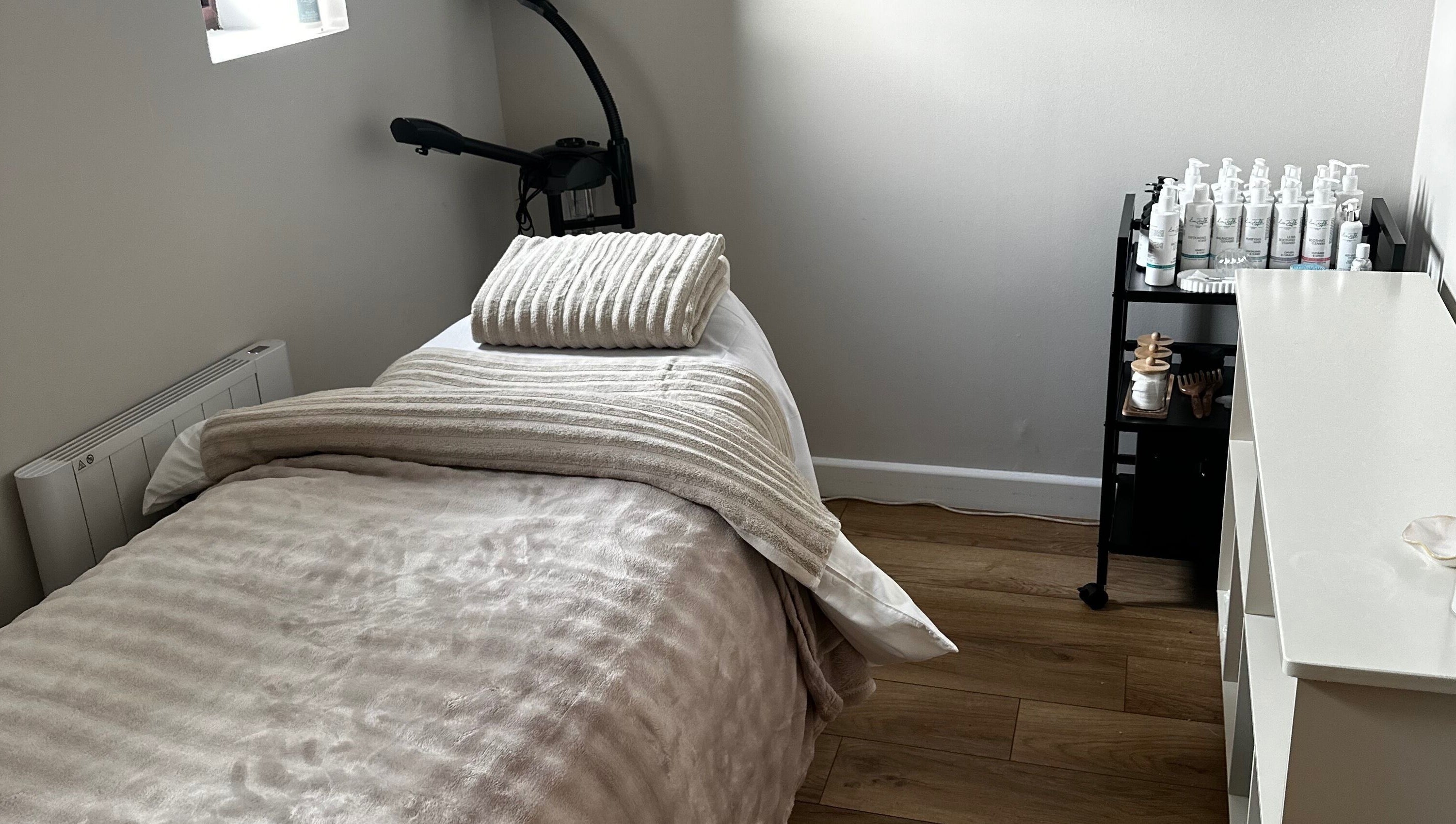 Tranquil spa room at Beauty by Claudie in Gamlingay, England, GB with cozy bed and beauty products.