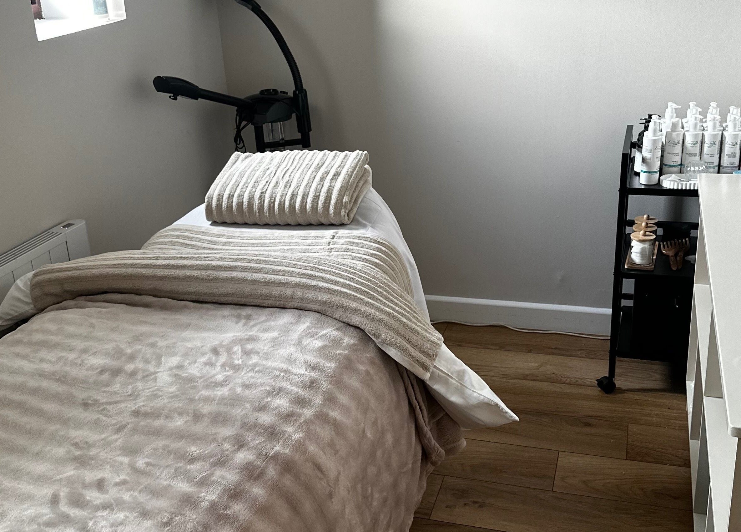 Tranquil spa room at Beauty by Claudie in Gamlingay, England, GB with cozy bed and beauty products.