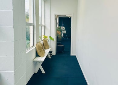 Light-filled hallway at Therapeia Limited in Auckland, Auckland, NZ, featuring cozy seating and potted plants.