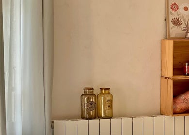 Coin chaleureux chez Camille Beauté Holistique, Maulichères, Occitanie, FR, avec rideaux, bouteilles et étagère.