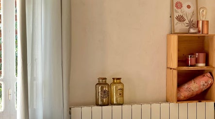 Coin chaleureux chez Camille Beauté Holistique, Maulichères, Occitanie, FR, avec rideaux, bouteilles et étagère.