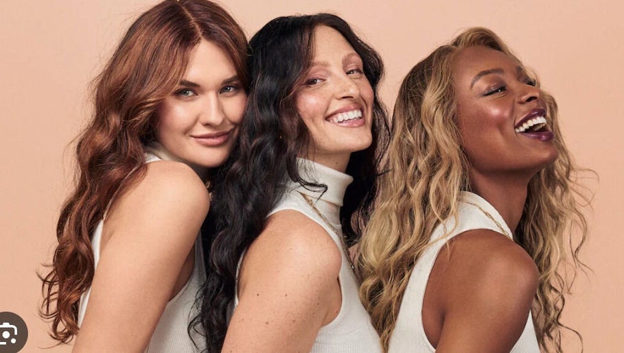 Three women smiling, showcasing diverse beauty at Amber Jean, London, England, GB.
