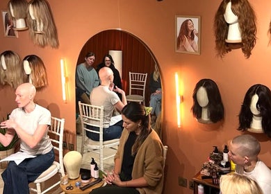 Amber Jean's wig workshop in London, England, GB with wigs on display and participants engaged in discussion.