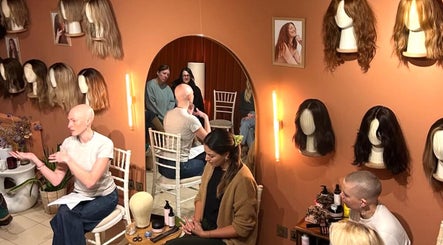 Amber Jean's wig workshop in London, England, GB with wigs on display and participants engaged in discussion.