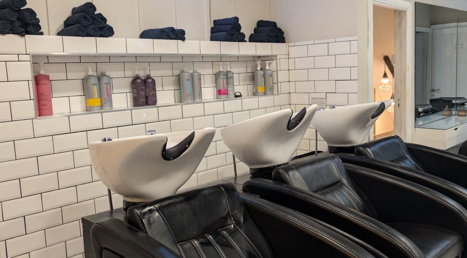Modern wash stations at Hair by Ava, Leeds, England. Stylish seating and premium products on display.