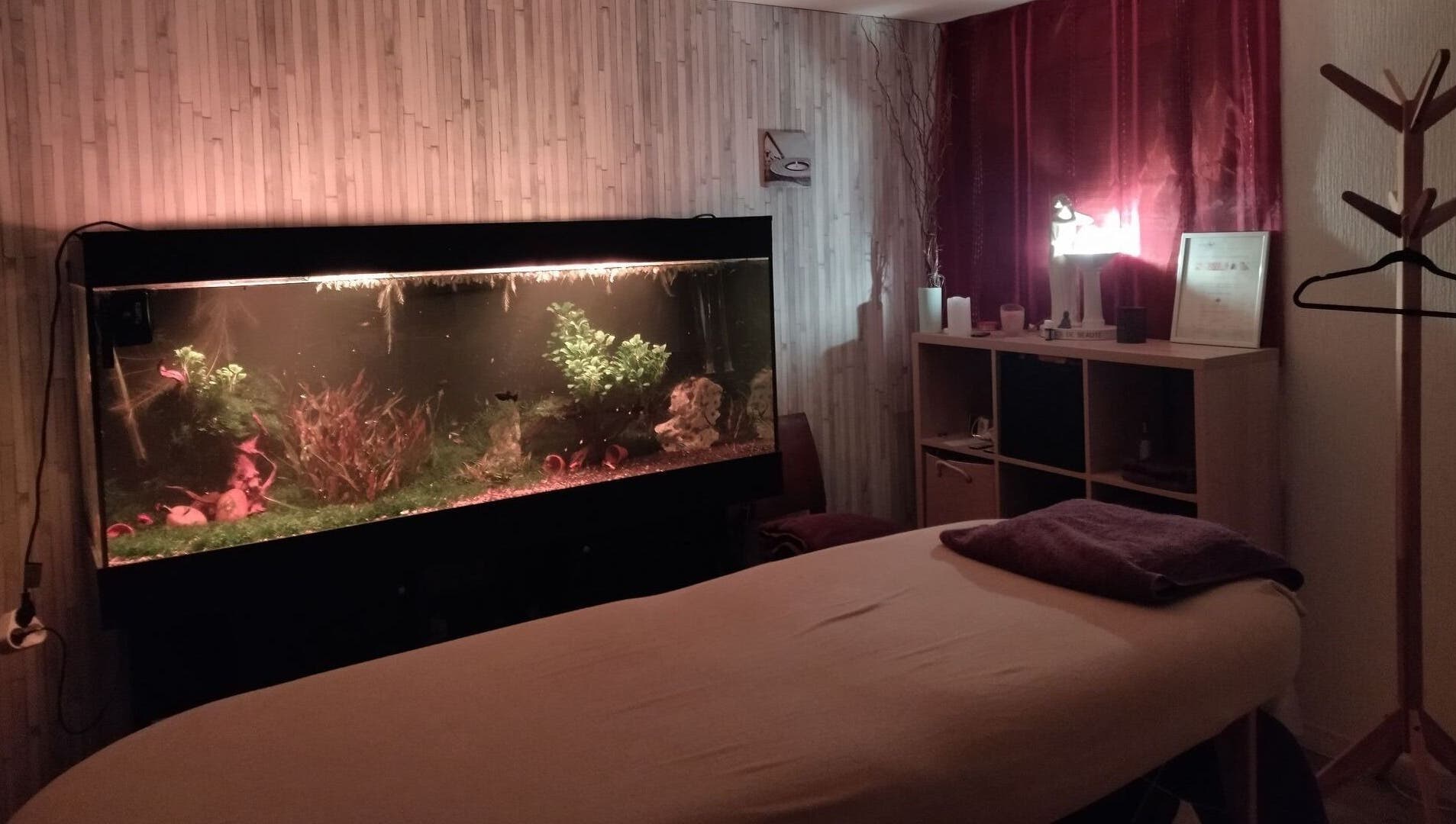 Salle de massage relaxante avec aquarium éclairé chez Zen-Shi, Hayange, Grand Est, FR.