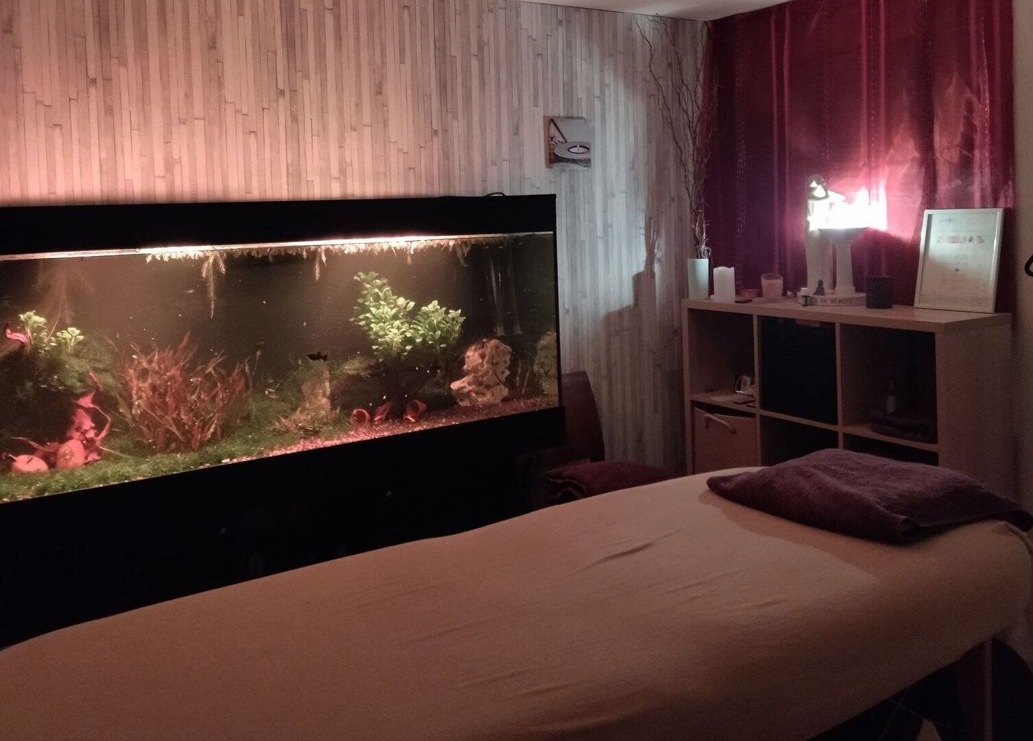 Salle de massage relaxante avec aquarium éclairé chez Zen-Shi, Hayange, Grand Est, FR.