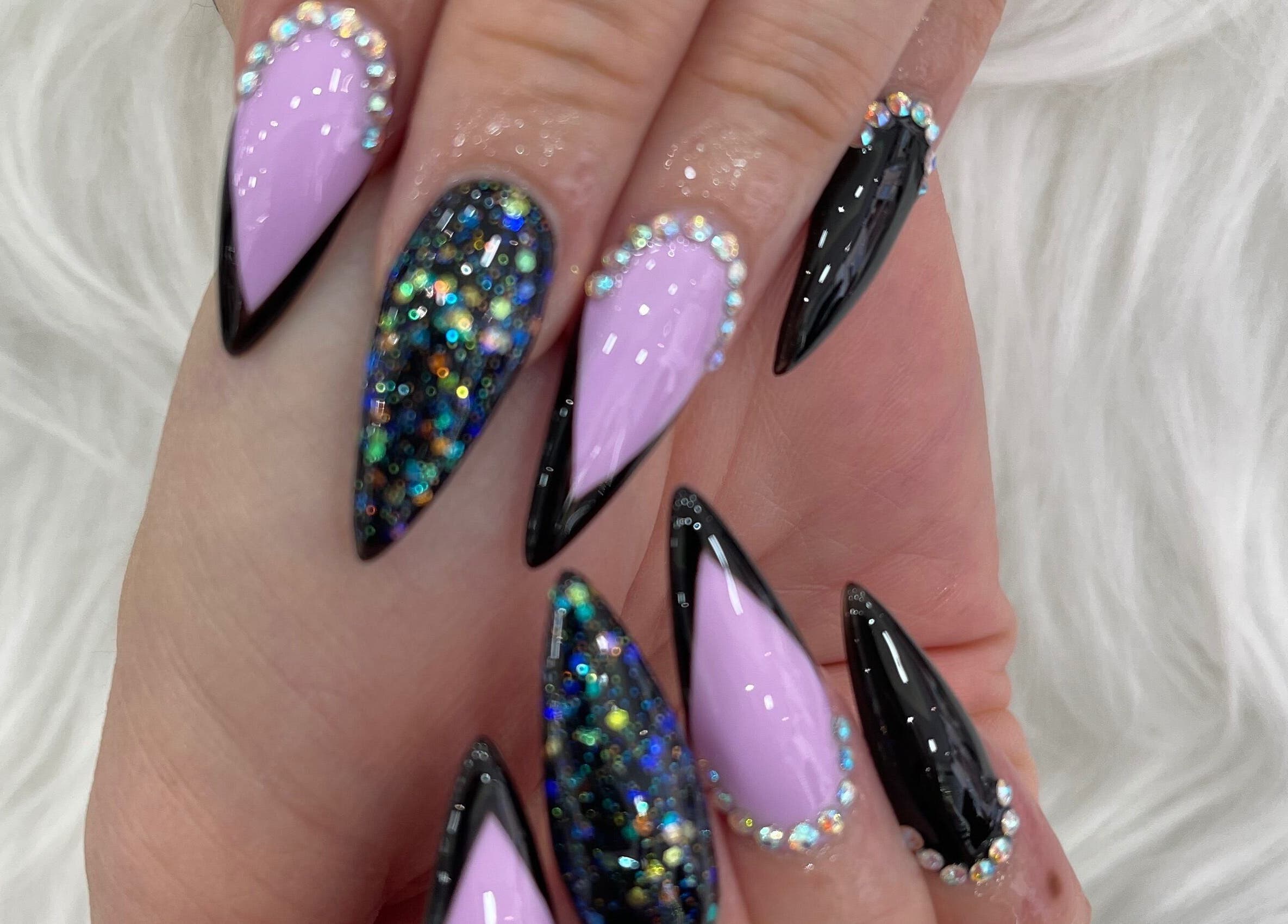 Elegant stiletto nails with black and glittery designs at MK Nails and Spa Fulham Ltd, London, England, GB.