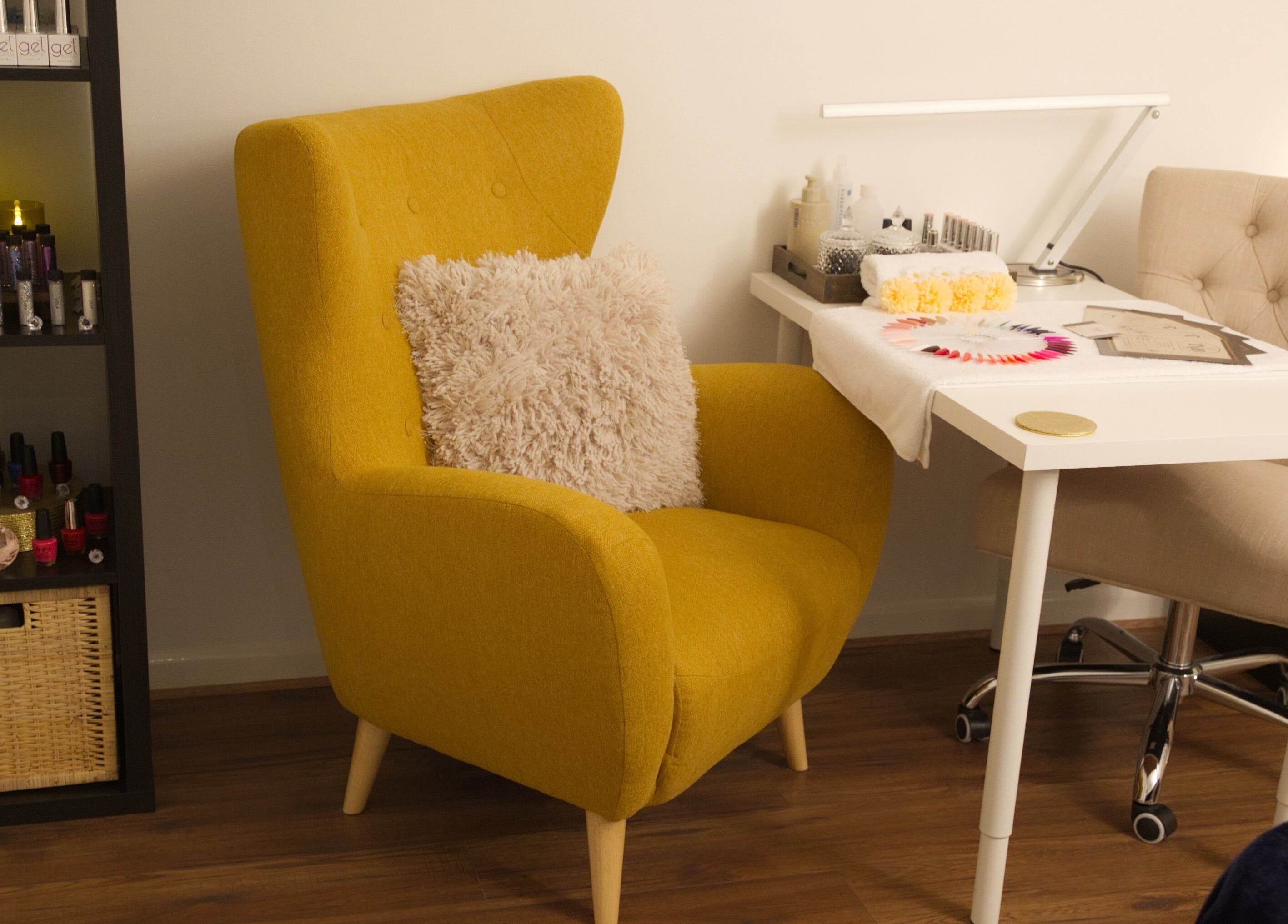 Inviting nail station at TMB Beauty, Brighton, GB with plush mustard chair and organized polish display.