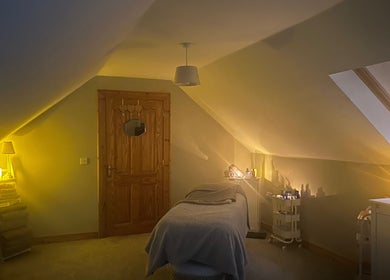 Cozy spa room at Swannlodge Beauty, Limavady, Northern Ireland, GB with ambient lighting and a massage table.