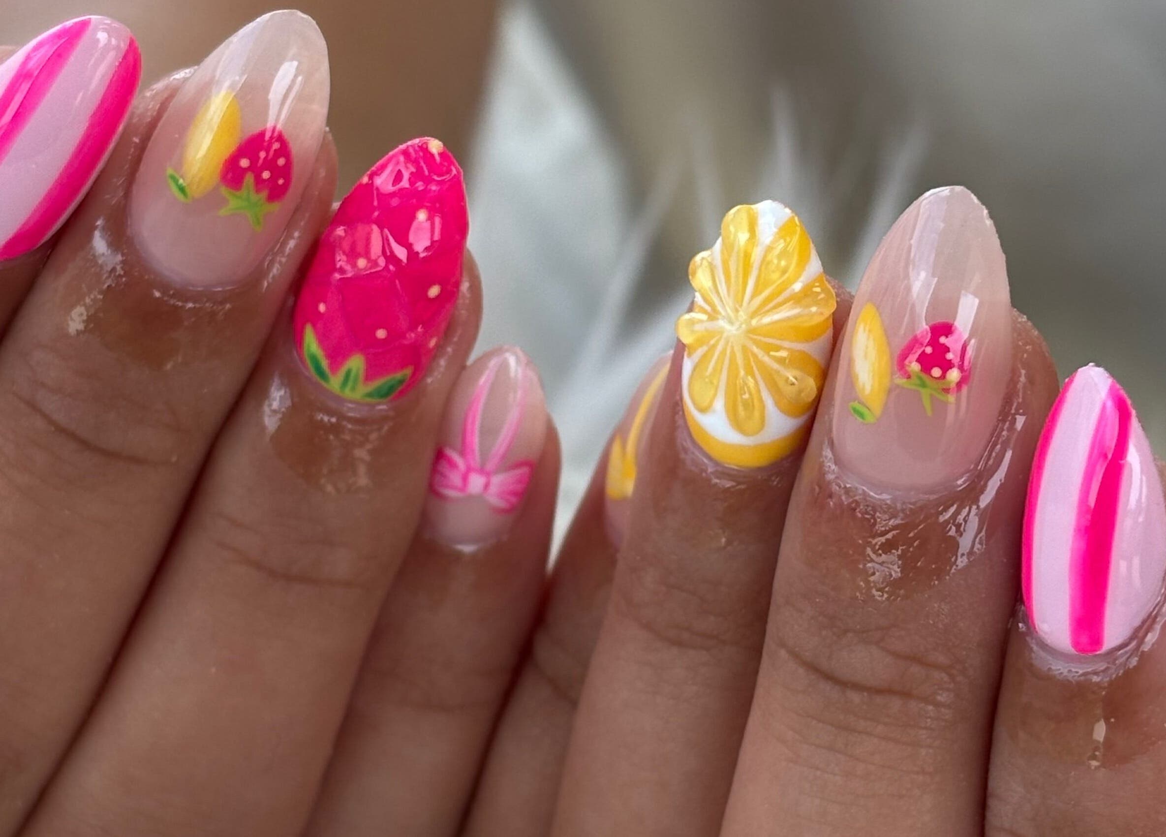 Vibrant tropical nail art at Anaya & CO., Saint James, Missouri, US. Featuring fruit designs with pink and yellow accents.