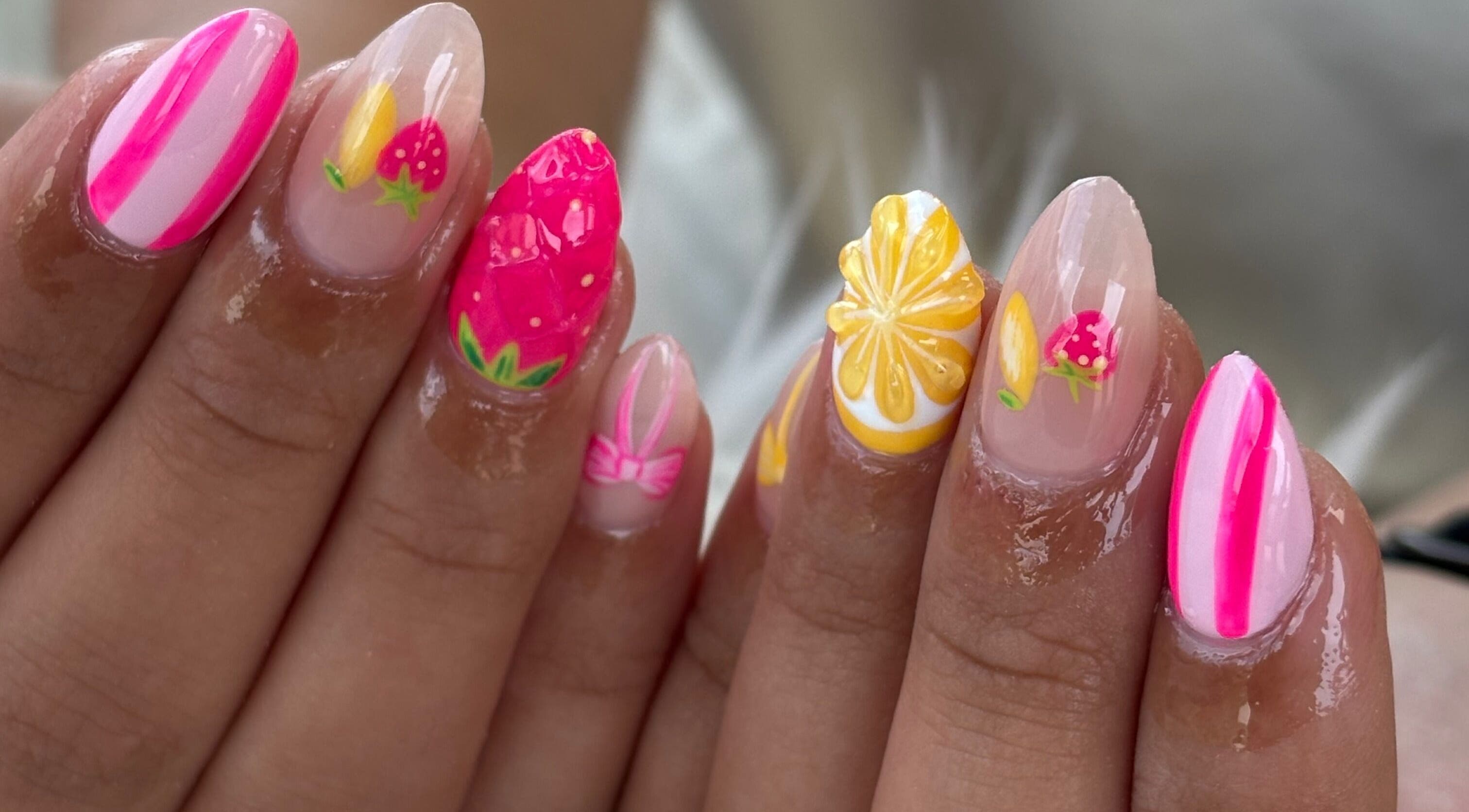 Vibrant tropical nail art at Anaya & CO., Saint James, Missouri, US. Featuring fruit designs with pink and yellow accents.