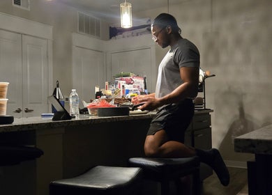 A person in a dimly lit kitchen at Sach Hair Braiding, Houston, TX, US.