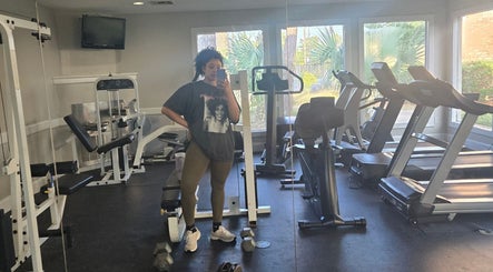 Woman in gym at Sach Hair Braiding, Houston, TX, US, surrounded by fitness equipment.