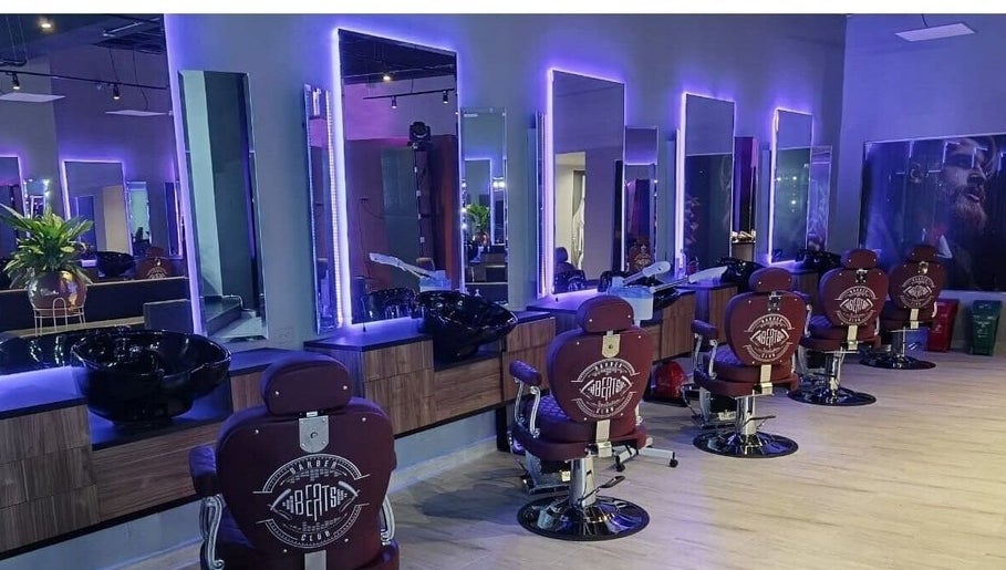 Interior del salón mbh en Barranquilla, CO, con luces elegantes y sillas de barbero modernas.