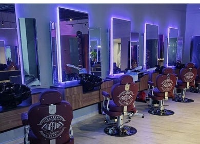 Interior moderno del salón mbh en Barranquilla, CO, con sillas elegantes y espejos iluminados.