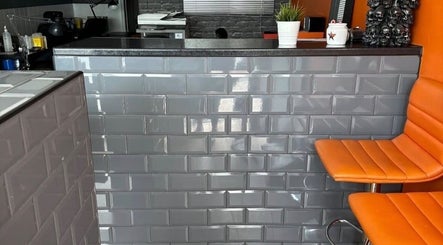 Stylish reception at Mind Over Matter Tattoo Studio, Hazel Grove, England, GB with modern decor and orange seating.