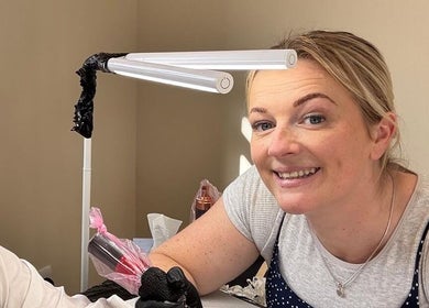 Tattoo artist smiling during a session at Inklet studio, Dunmow, England, GB.