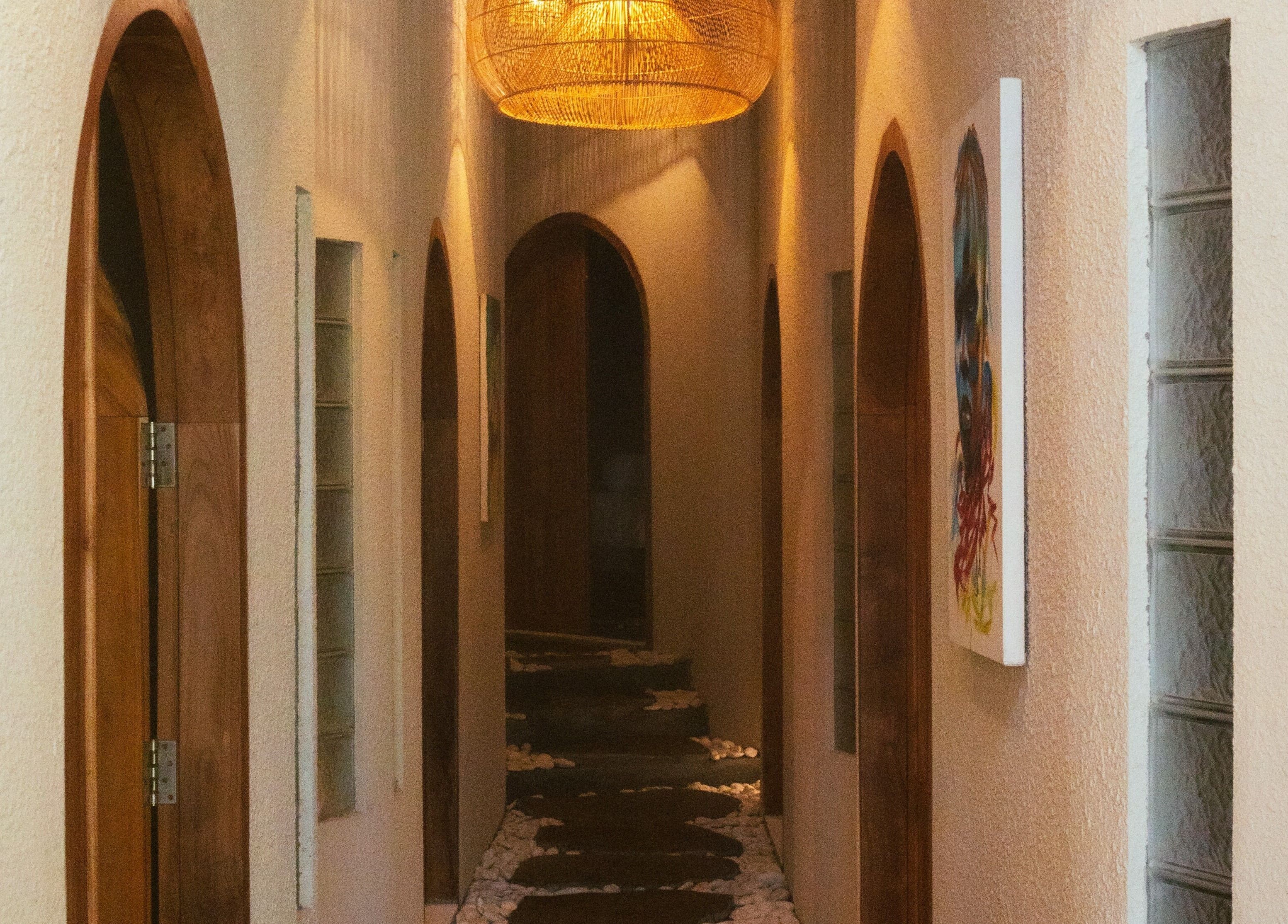 Коридор с мягким освещением в Raya Spa, Бали, Бали, ID с деревянными дверями и картинами.