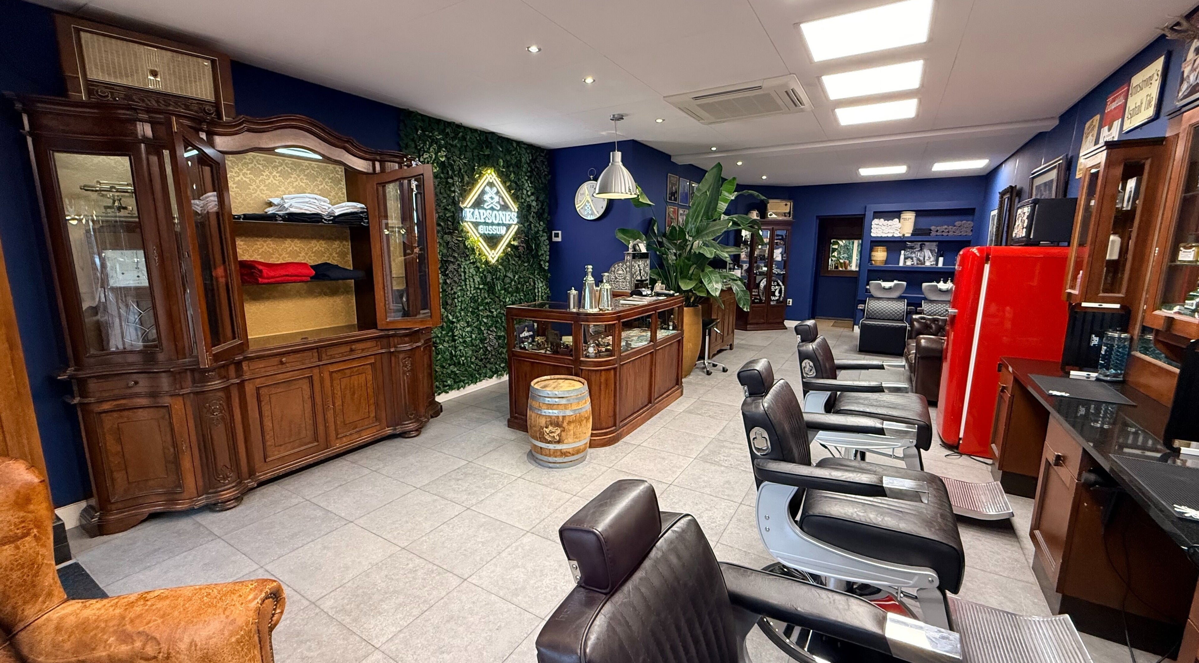 Stijlvolle interieur van Kapsones in Bussum, Noord-Holland, NL met luxe kappersstoelen en antieke meubels.