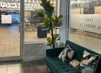 Welcoming seating area at Cove Tanning Studio, Droitwich Spa, England with green sofa and bright window.