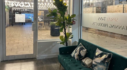 Welcoming seating area at Cove Tanning Studio, Droitwich Spa, England with green sofa and bright window.