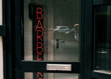 Neon barber sign in window of DTRHair, Newcastle upon Tyne, England, GB, showcasing stylish entrance.