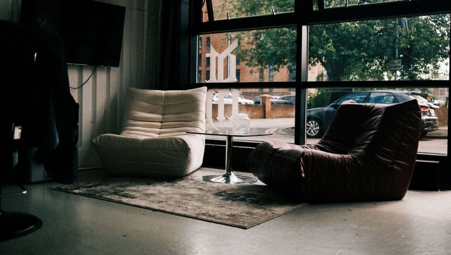 Stylish seating area in DTRHair, Newcastle upon Tyne, England, GB featuring modern chairs and a glass table.