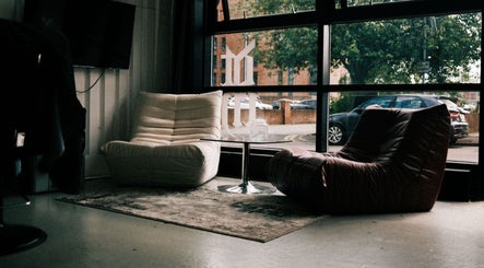 Stylish seating area in DTRHair, Newcastle upon Tyne, England, GB featuring modern chairs and a glass table.
