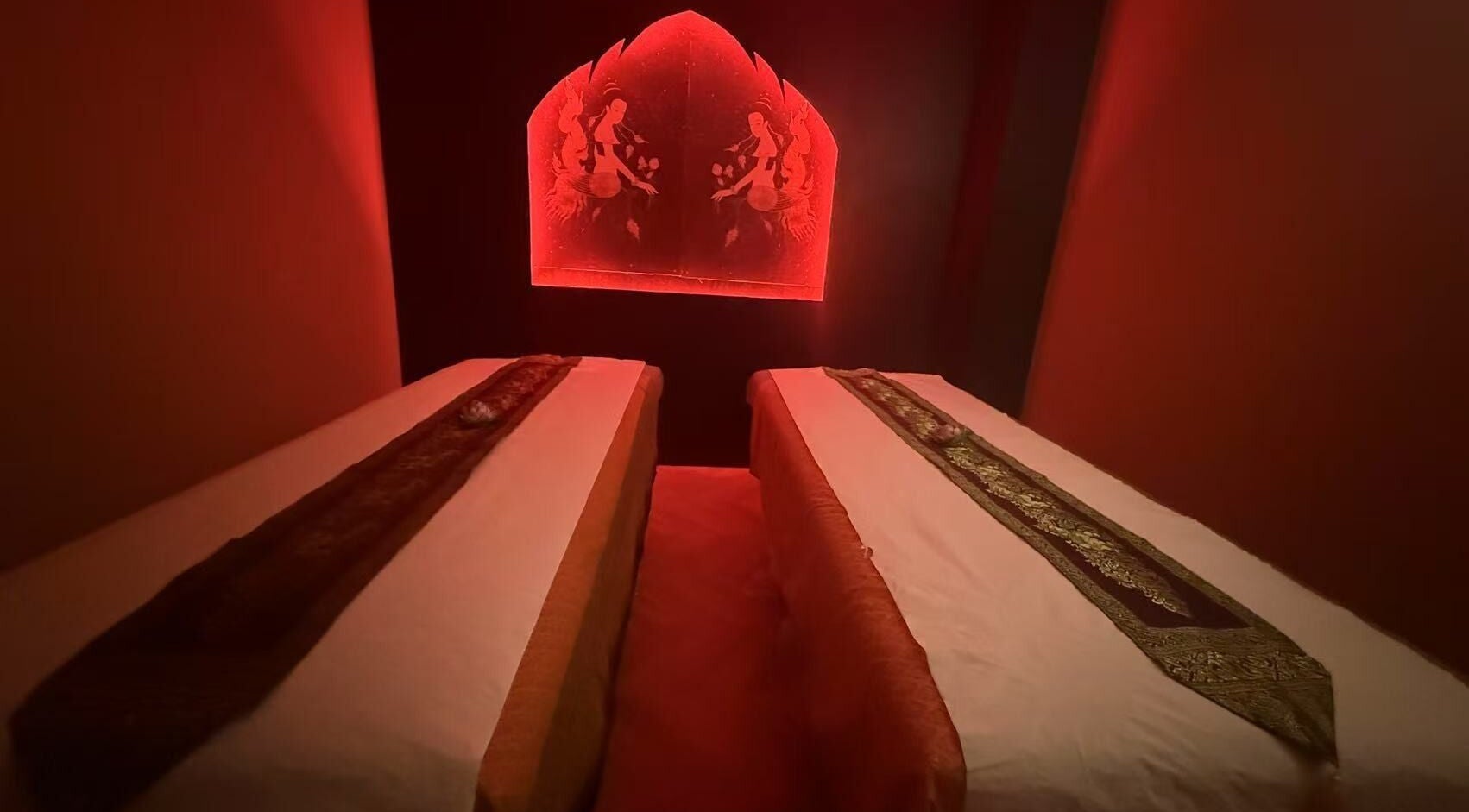 Salle de massage apaisante à THAI SWAN SPA, Paris, Île-de-France, FR, avec lumière rouge tamisée.