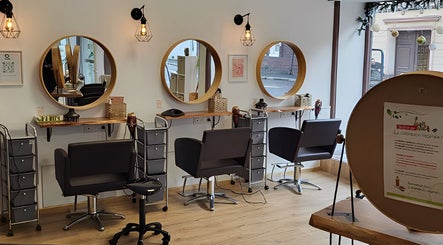 Intérieur moderne de Biocoiff Rouen à Rouen, Normandie, FR avec miroirs circulaires et chaises confortables.