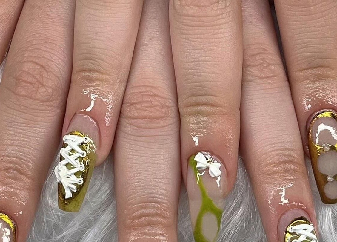 Intricate nail art design at ClawzbyLau, Canelones, Departamento De Canelones, UY featuring gold and white accents.