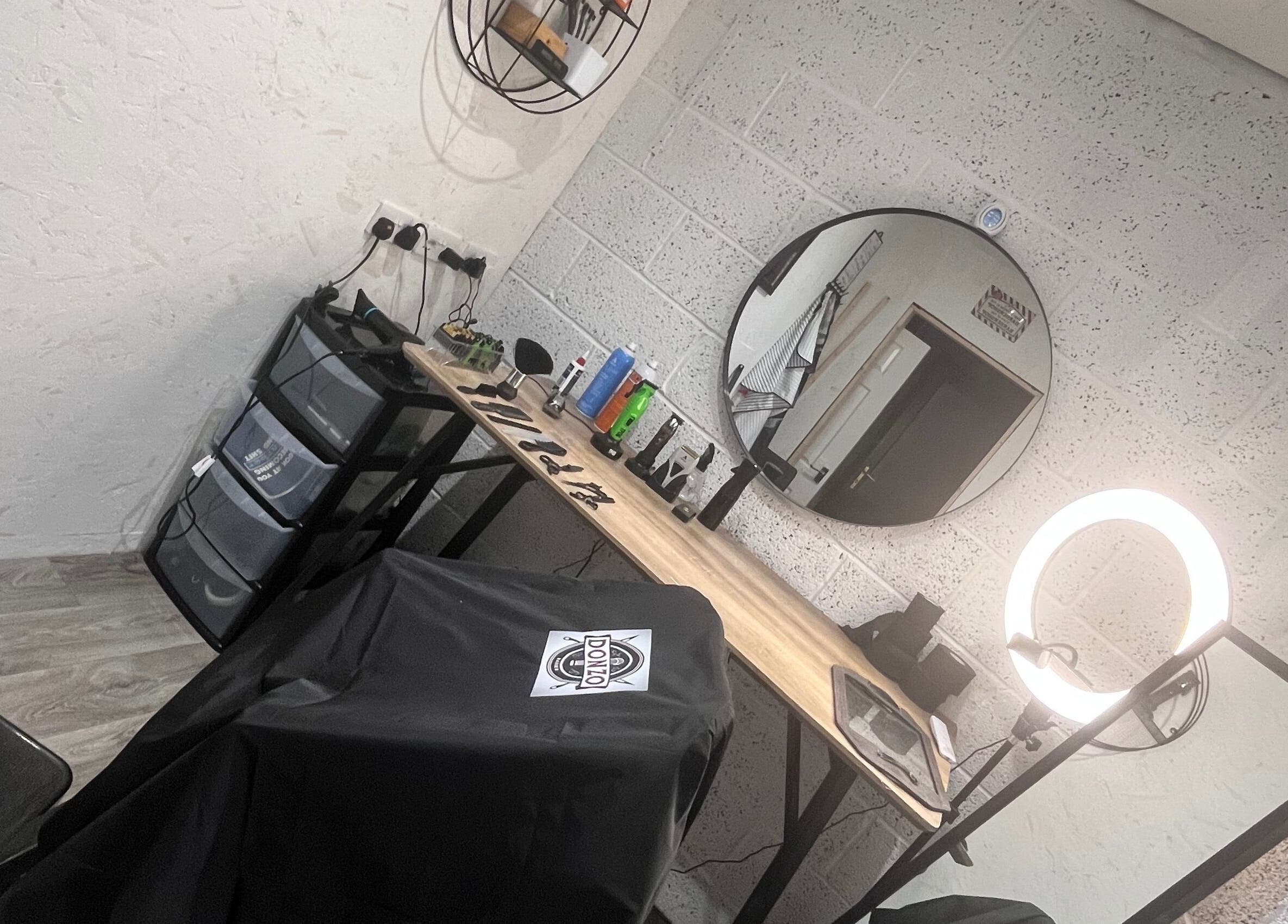 Modern barber station at Donzos_cuts, Pembroke, Wales, GB with mirror, ring light, and grooming tools.