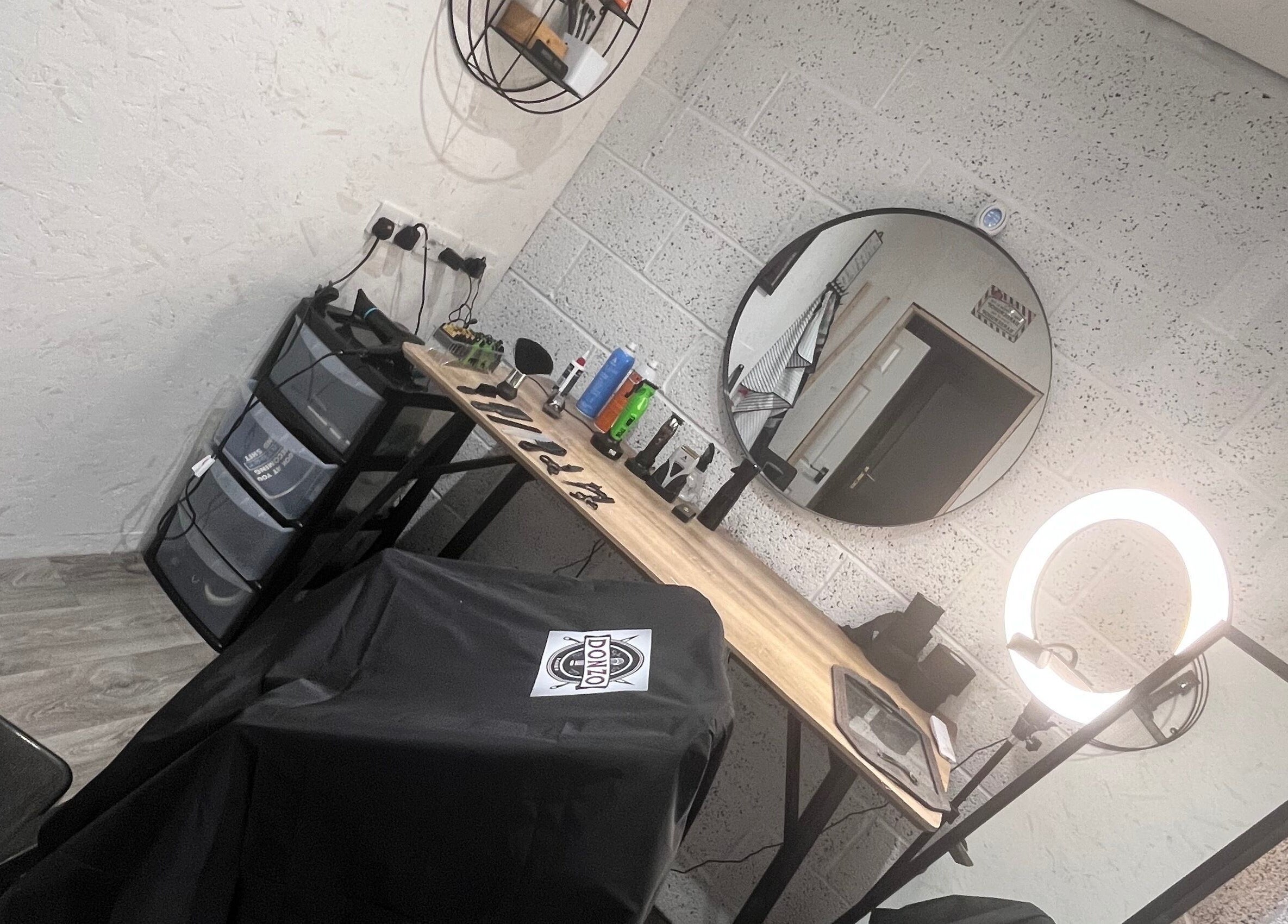 Modern barber station at Donzos_cuts, Pembroke, Wales, GB with mirror, ring light, and grooming tools.