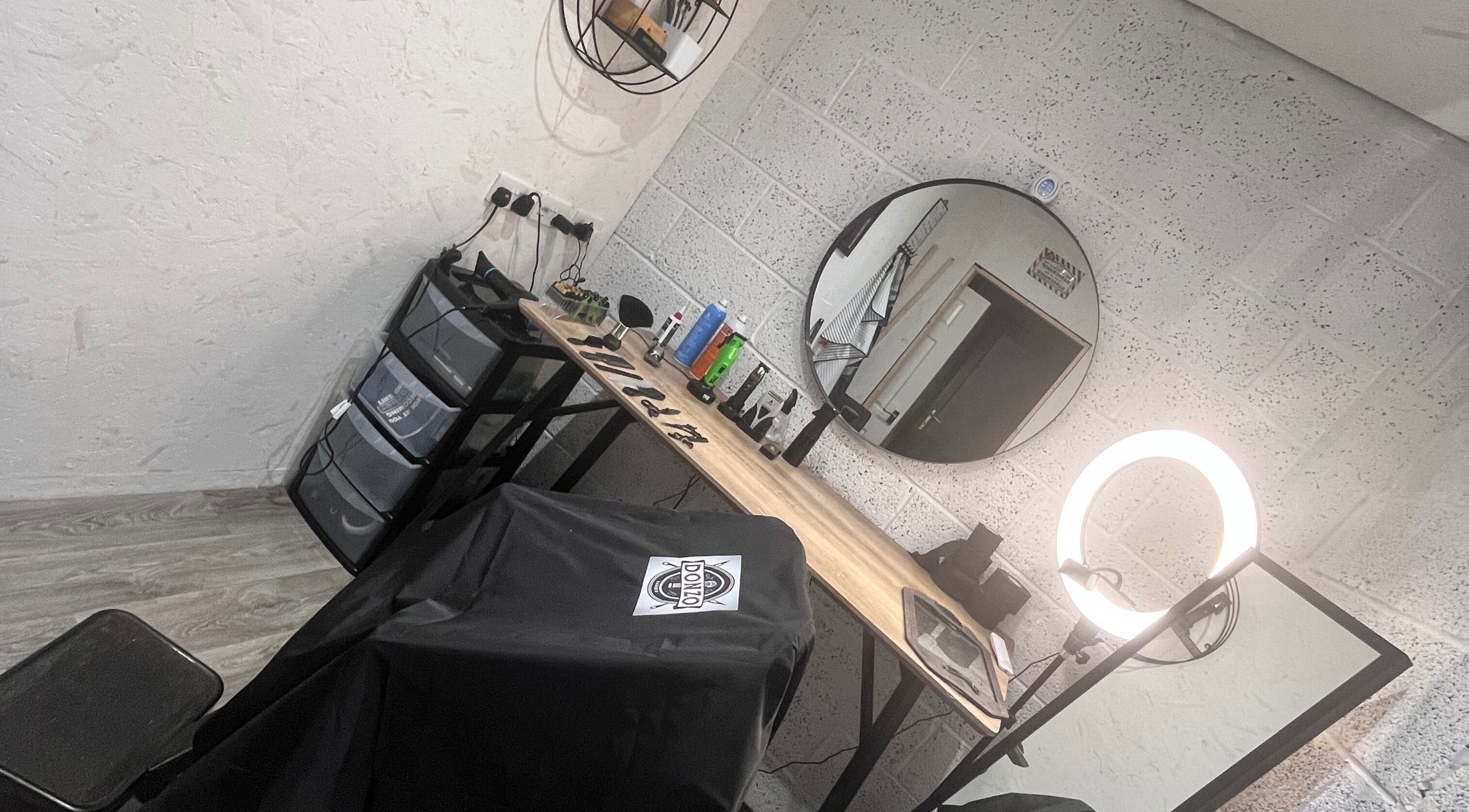 Modern barber station at Donzos_cuts, Pembroke, Wales, GB with mirror, ring light, and grooming tools.