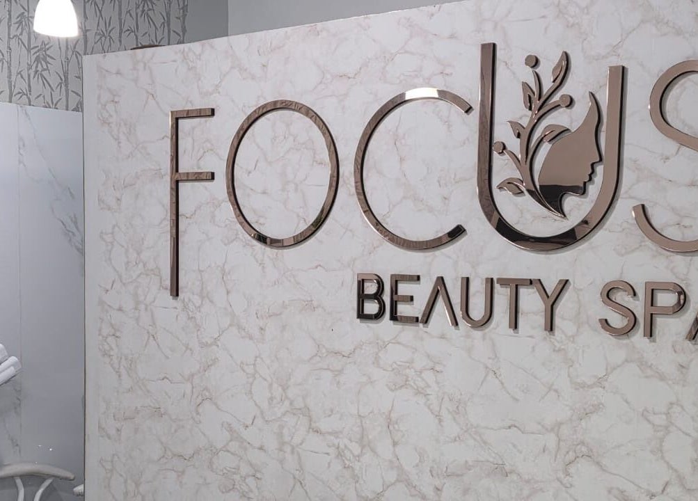 Interior de FOCUS BEAUTY SPA en Caracas, Miranda, VE, destacando su elegante logotipo en la pared de mármol.