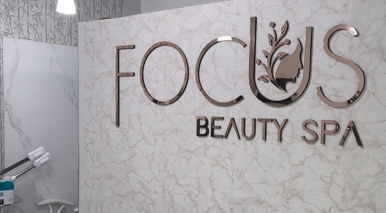 Interior de FOCUS BEAUTY SPA en Caracas, Miranda, VE, destacando su elegante logotipo en la pared de mármol.