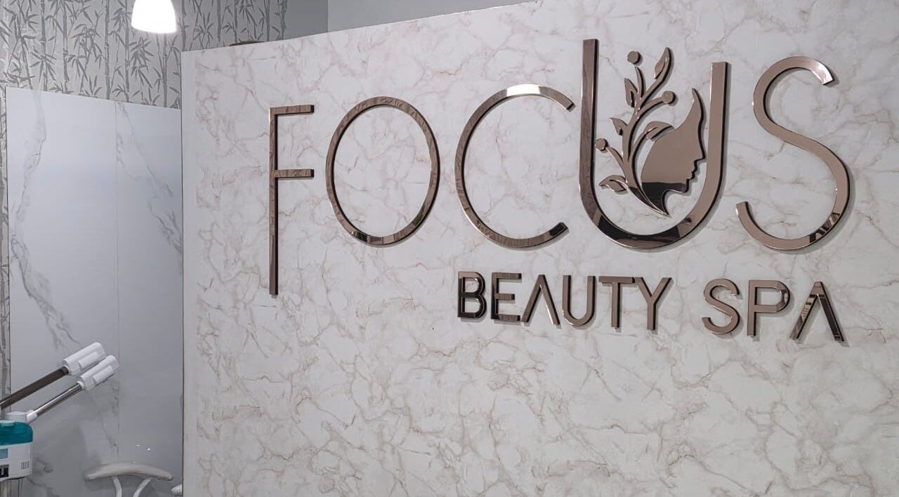Interior de FOCUS BEAUTY SPA en Caracas, Miranda, VE, destacando su elegante logotipo en la pared de mármol.