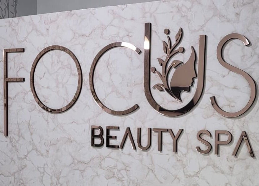 Logo metálico de FOCUS BEAUTY SPA en pared de mármol en Caracas, Miranda, VE.