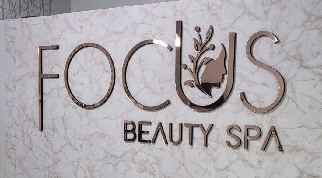 Logo metálico de FOCUS BEAUTY SPA en pared de mármol en Caracas, Miranda, VE.