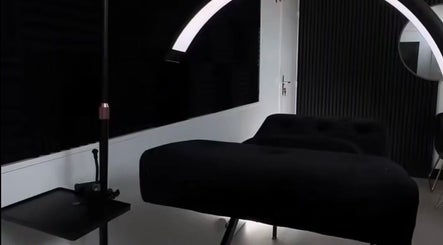 Modern beauty treatment room at Ré-luxe Beauty, Mitcham, England, GB, featuring sleek black furniture and lighting.