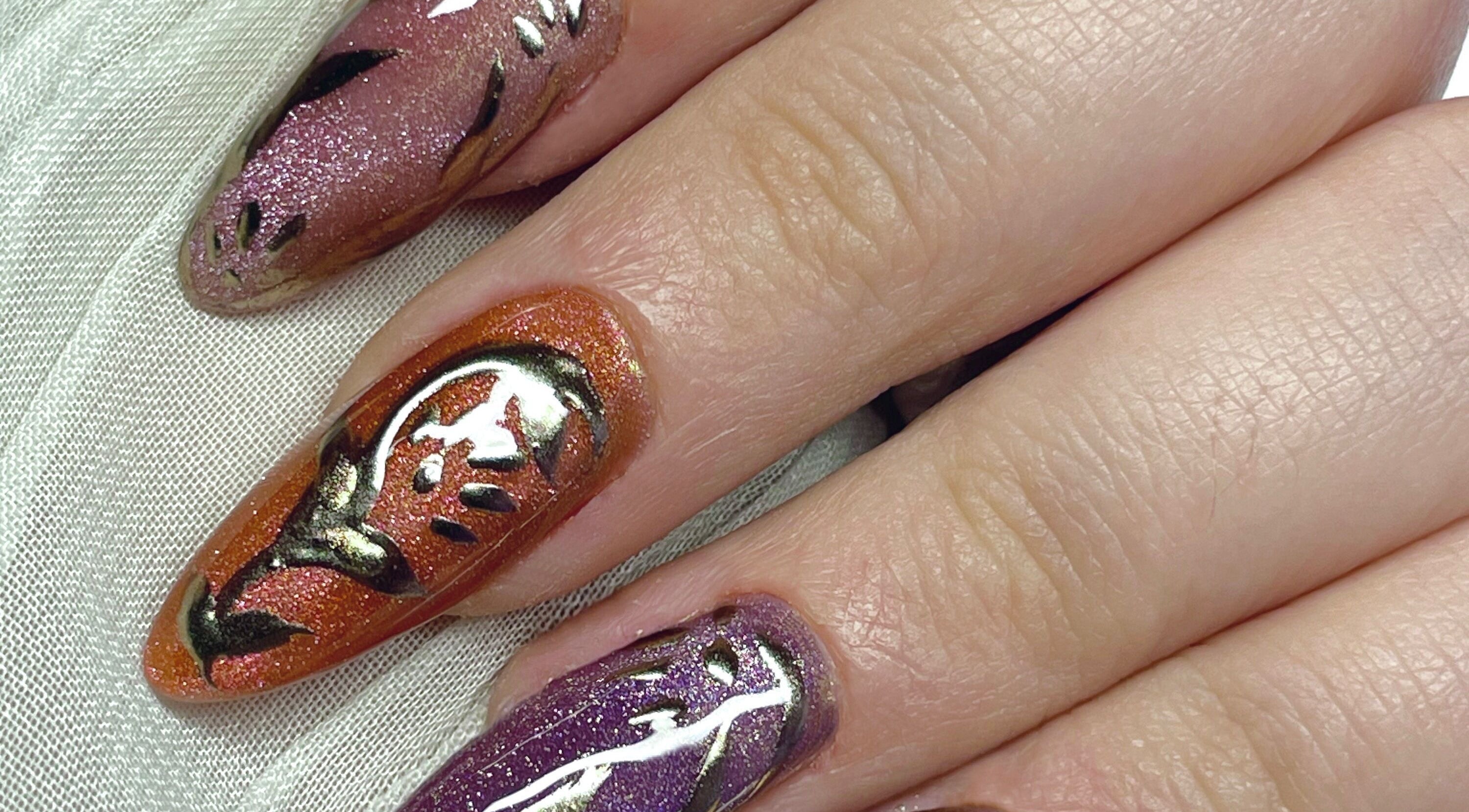 Intricate nail art at Studio Kay At Gloss and Glow, Il-Mosta, MT, showcasing detailed designs in purple and orange.