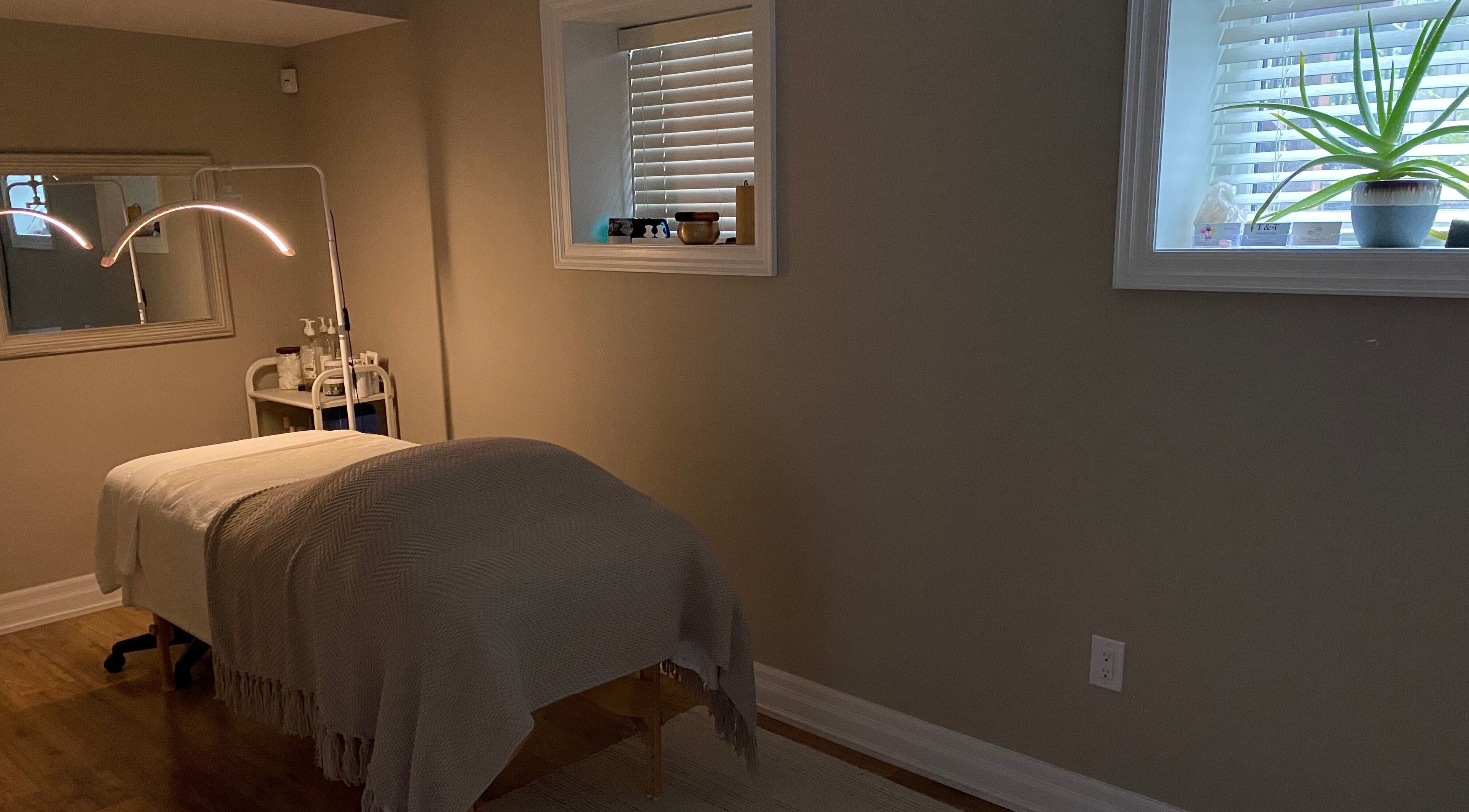 Cozy spa treatment room at The Glowing Angel, Toronto, Ontario, CA featuring a massage bed under warm lighting.