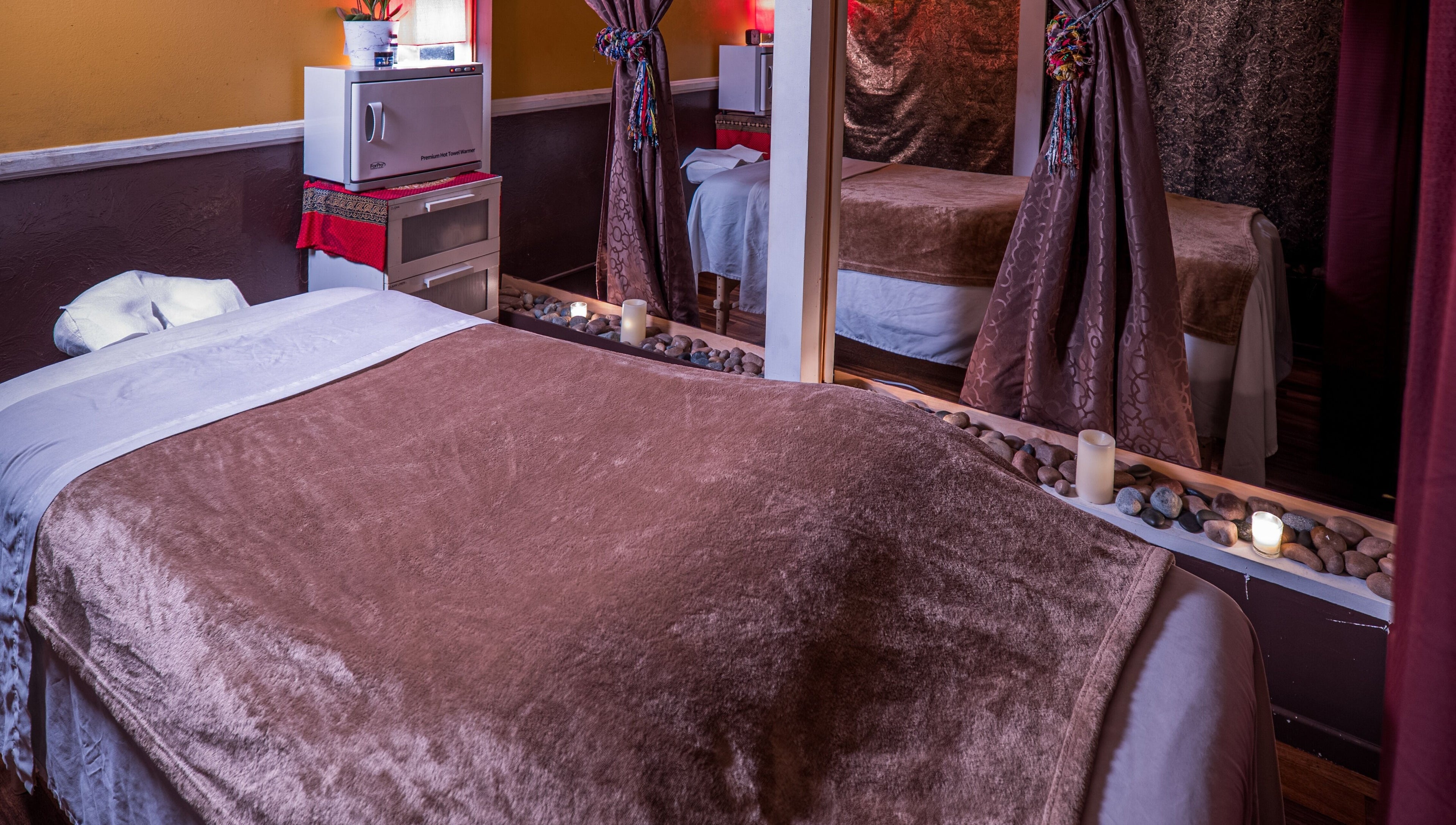 Tranquil massage room at The ZenSai Spa, Burbank, California, US, featuring plush bedding and ambient lighting.