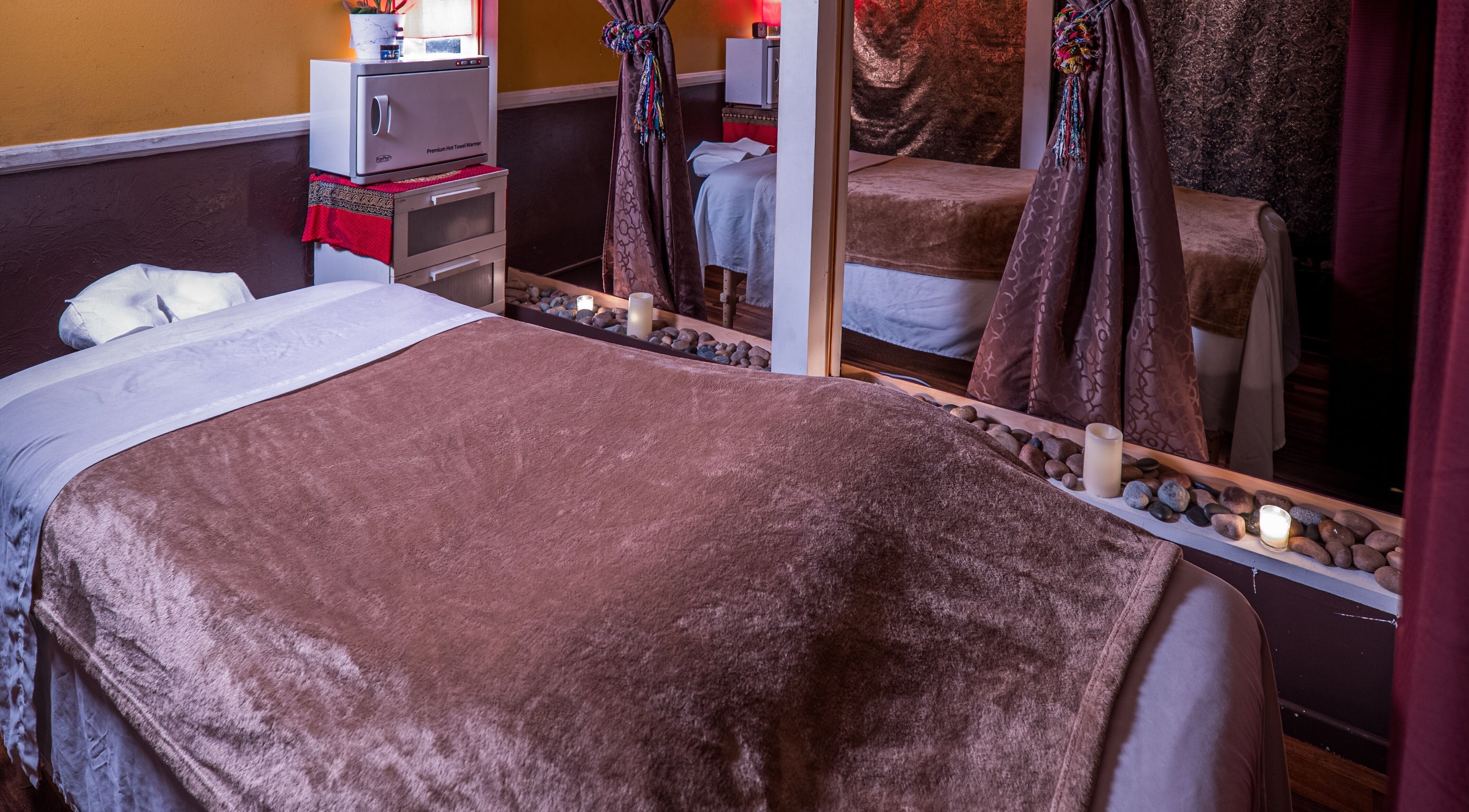 Tranquil massage room at The ZenSai Spa, Burbank, California, US, featuring plush bedding and ambient lighting.