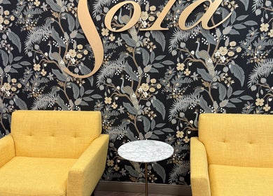 Stylish seating area at Men's Grooming Lounge By Mel, Mission Viejo, California, US with floral wallpaper.