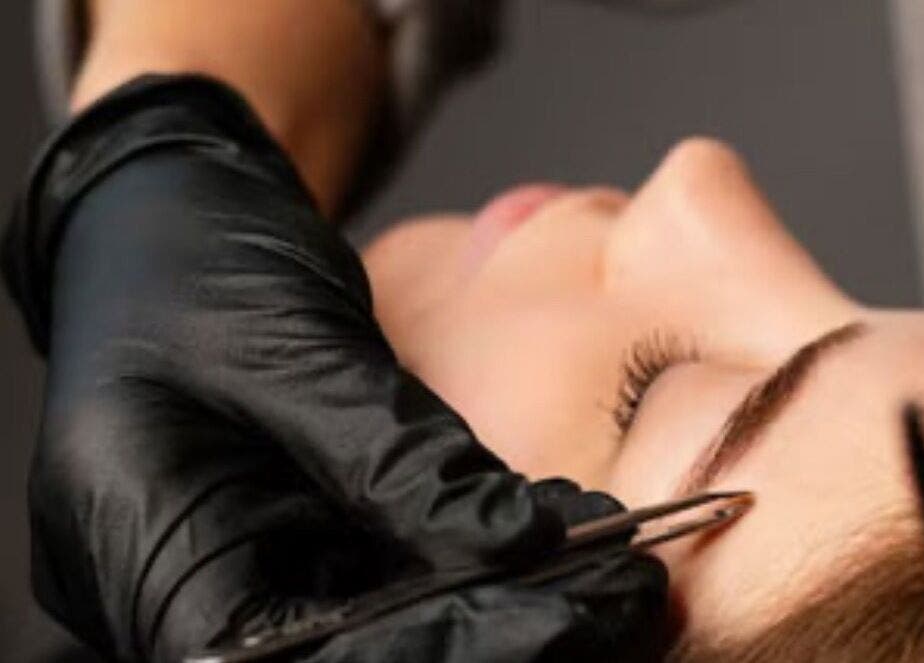 Eyebrow shaping at Lash & Brow Haven, Brisbane, Queensland, AU. A hand tweezes a client's eyebrow.