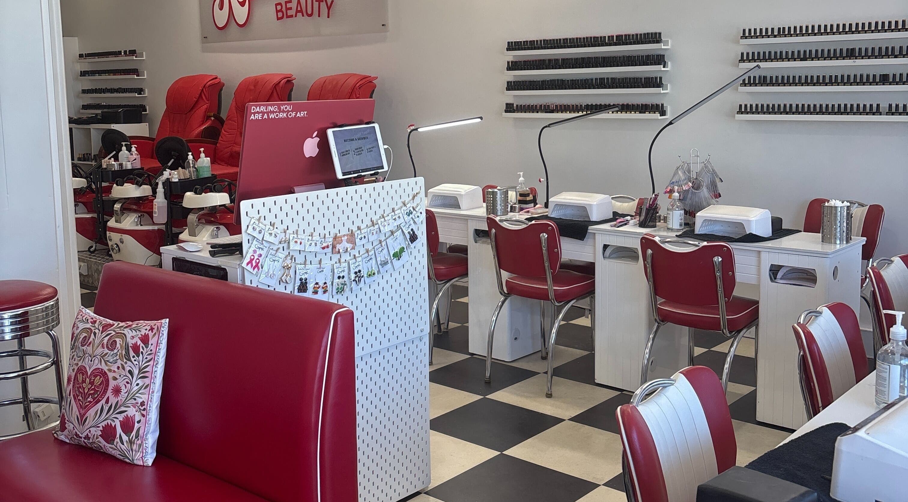 Rockabella Beauty salon interior at Attadale, Western Australia, AU, featuring stylish red and white chairs and nail stations.