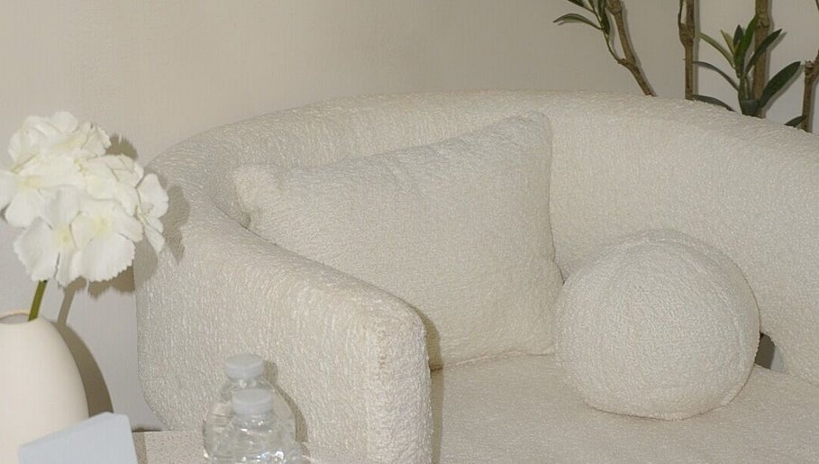 Sofá blanco acogedor en Luarey Beauty Club, Ciudad Obregón, Sonora, MX, rodeado de flores blancas.