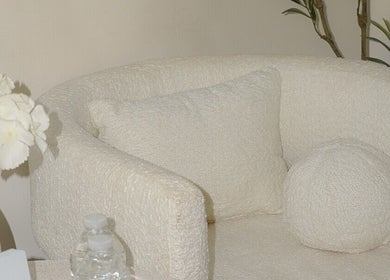 Sofá blanco acogedor en Luarey Beauty Club, Ciudad Obregón, Sonora, MX, rodeado de flores blancas.